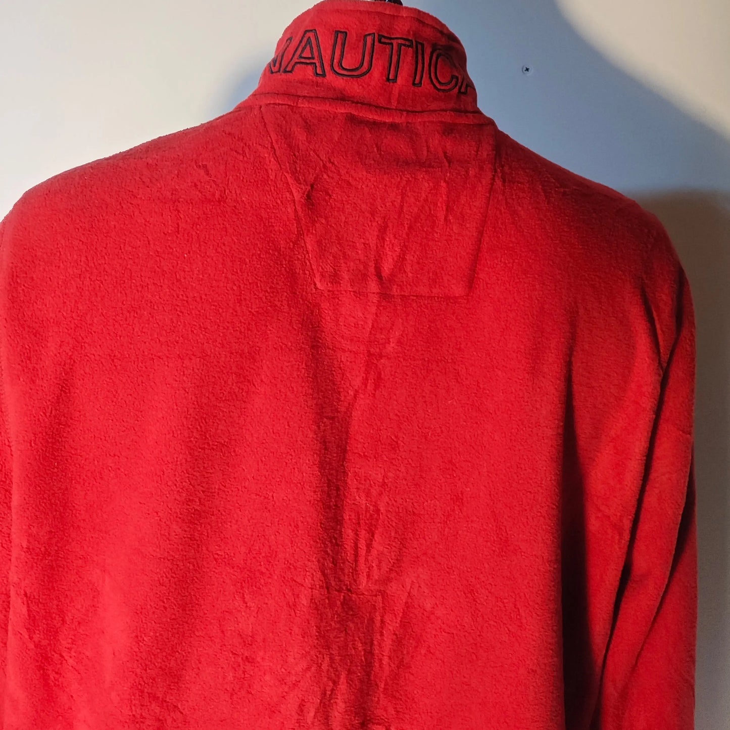 Veste polaire rouge par Nautica, avec inscription du logo noir sur le col, vue de dos.
