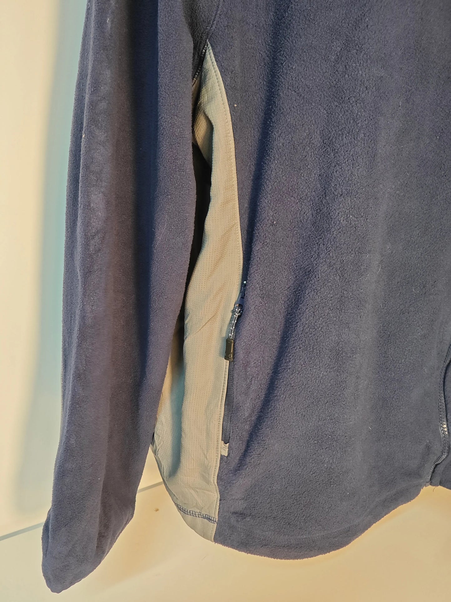 Veste polaire bleu marine et grise Skechers, avec fermeture éclair latérale, en tissu texturé.