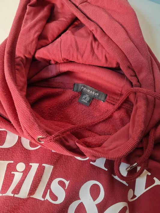 Sweat à capuche framboise oversize de Primark, avec cordon de serrage et inscription « Beverly Hills » blanche.
