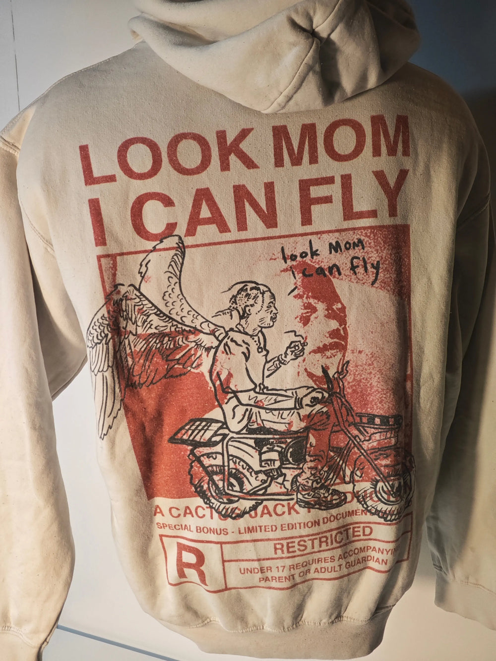 Sweat à capuche beige d'occasion de Travis Scott, avec inscription rouge « Look Mom I Can Fly » et graphiques imprimés au dos.
