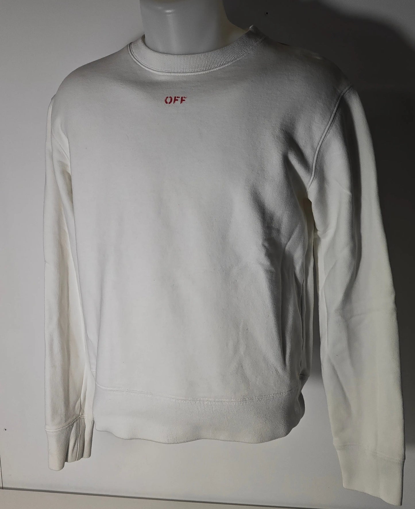 Sweat-shirt blanc, par Off-White, avec le mot « OFF » en rouge sur le devant.