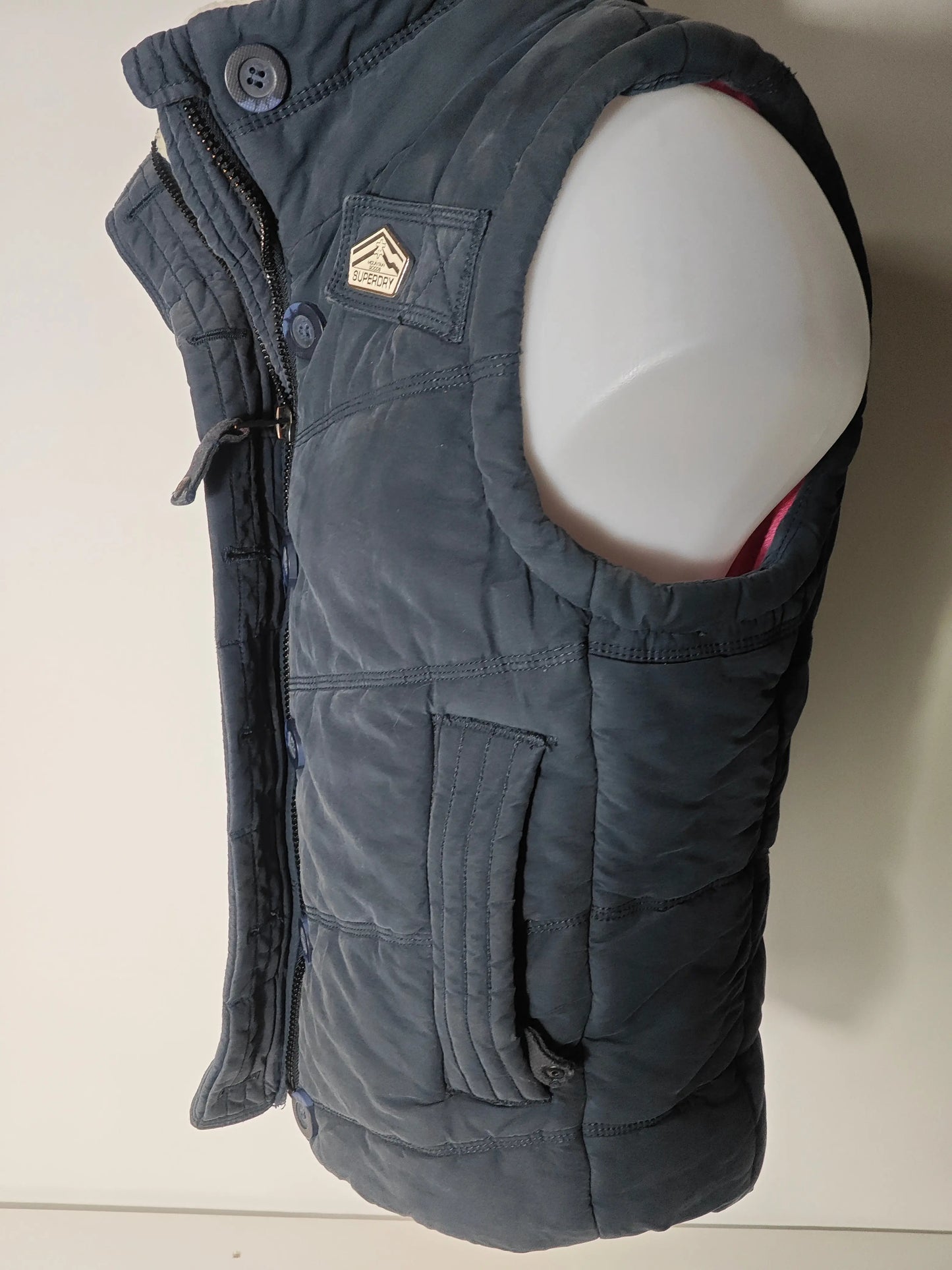 Doudoune sans manches bleue taille M de Superdry, avec fermeture éclair et poches, sur un mannequin.