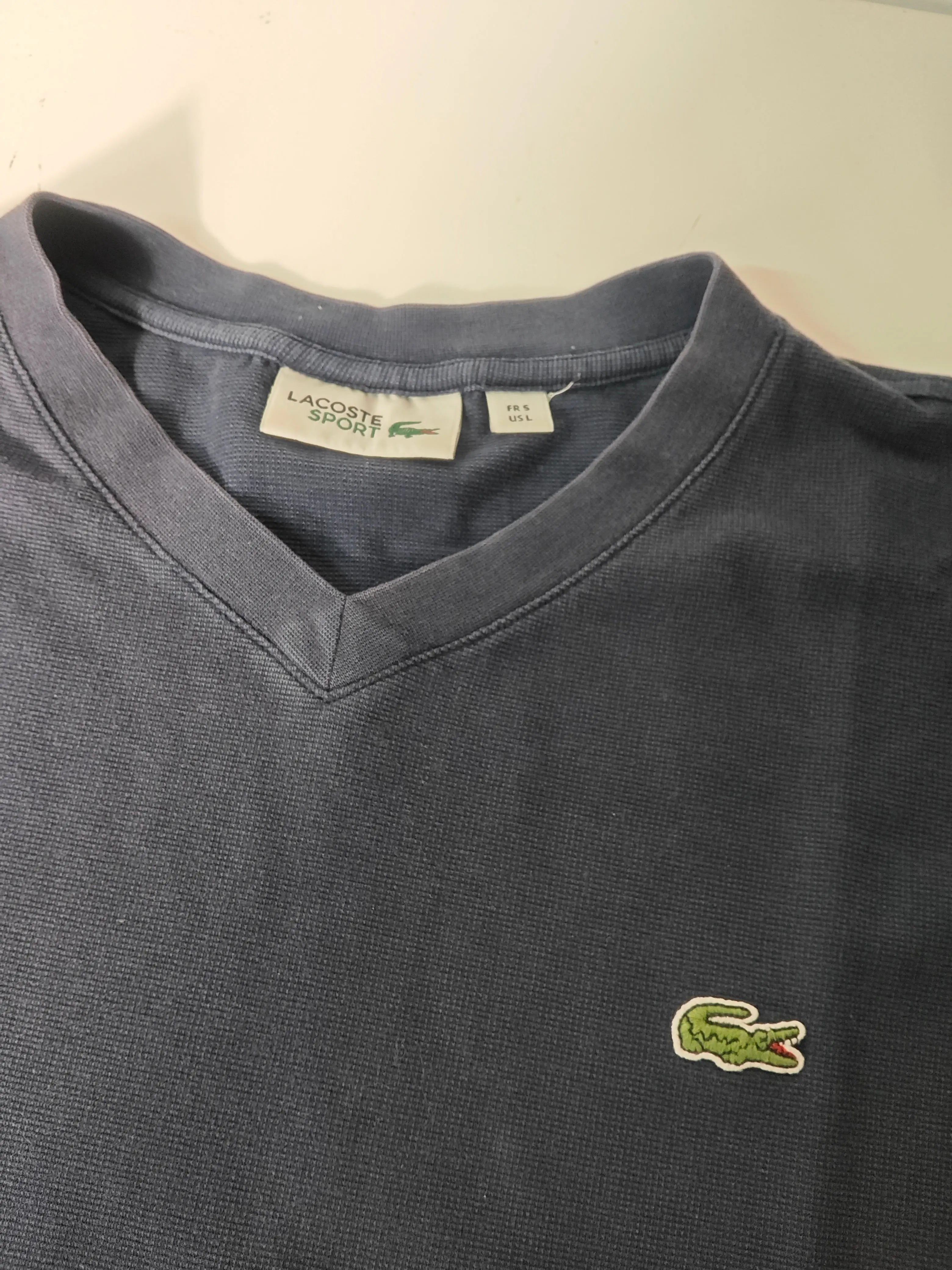 T-shirt bleu marine à col V Lacoste, avec logo crocodile brodé sur la poitrine.
