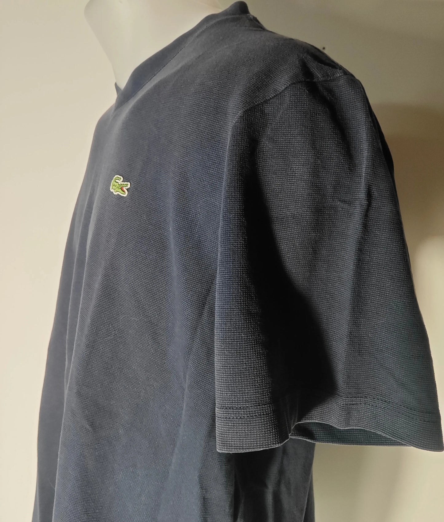T-shirt bleu marine à col V de Lacoste, avec un logo crocodile vert sur la poitrine.