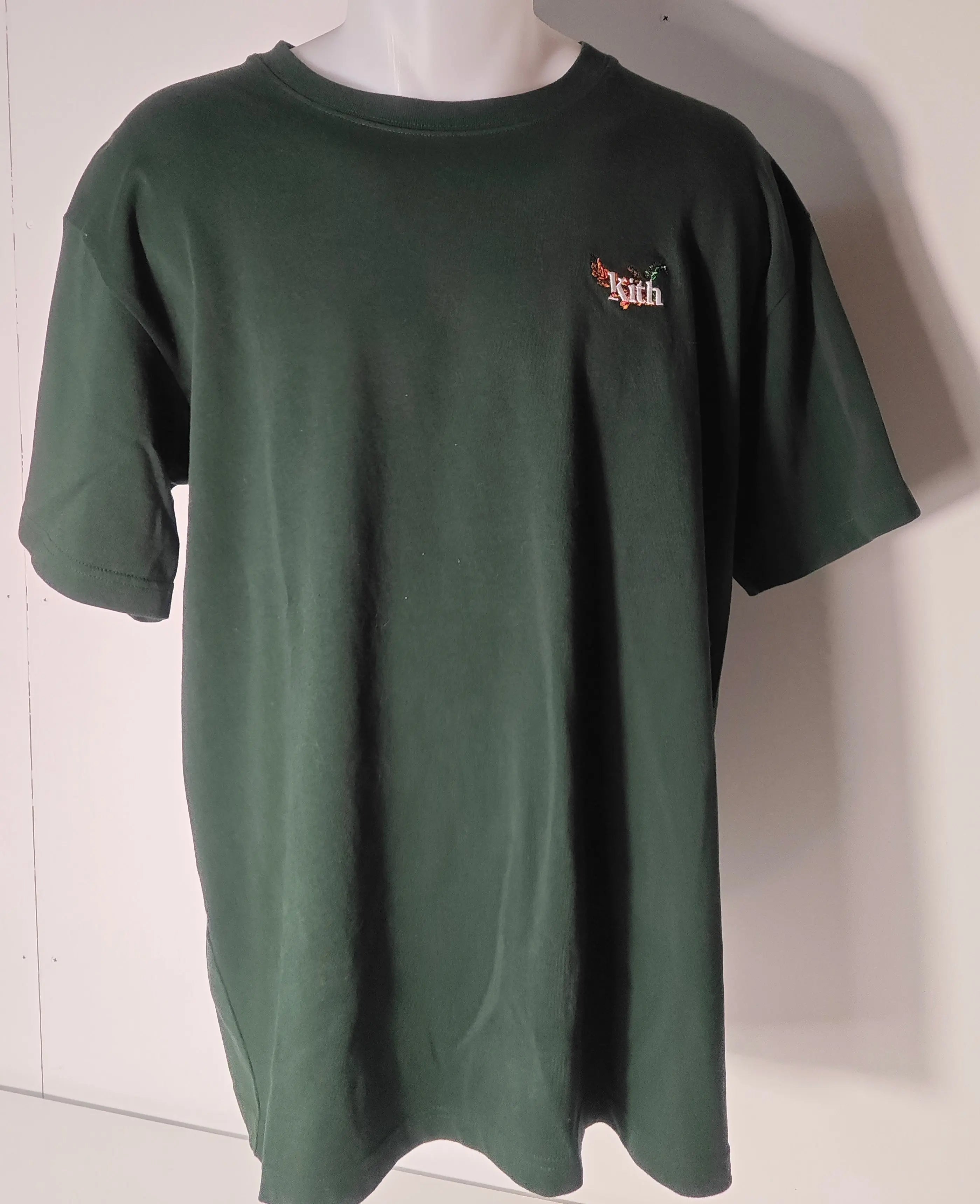 T-shirt vert foncé à logo floral brodé de Kith, présenté sur un mannequin.