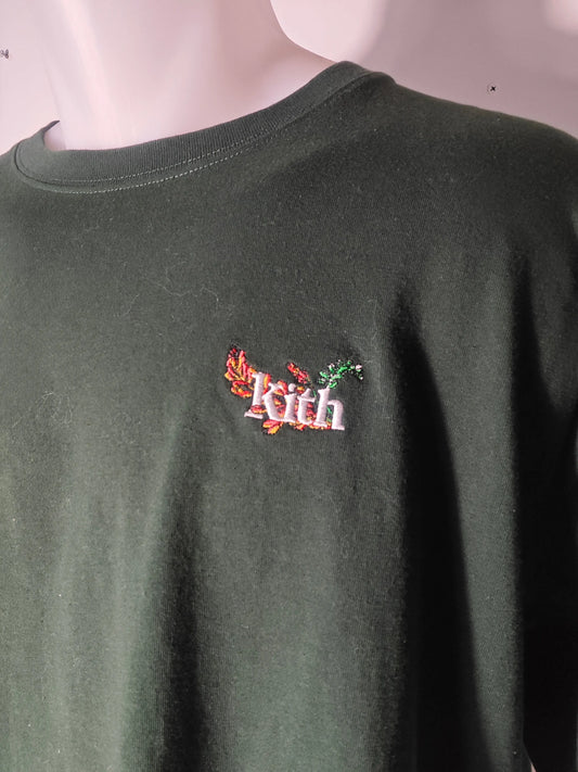 T-shirt vert foncé brodé d'un logo floral de Kith, porté sur un mannequin, avec encolure ras du cou.