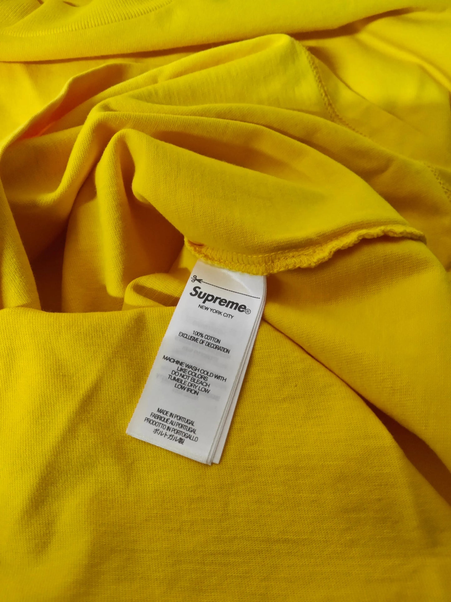 T-shirt jaune à manches longues de Supreme, avec une étiquette d'entretien visible et une texture en coton.
