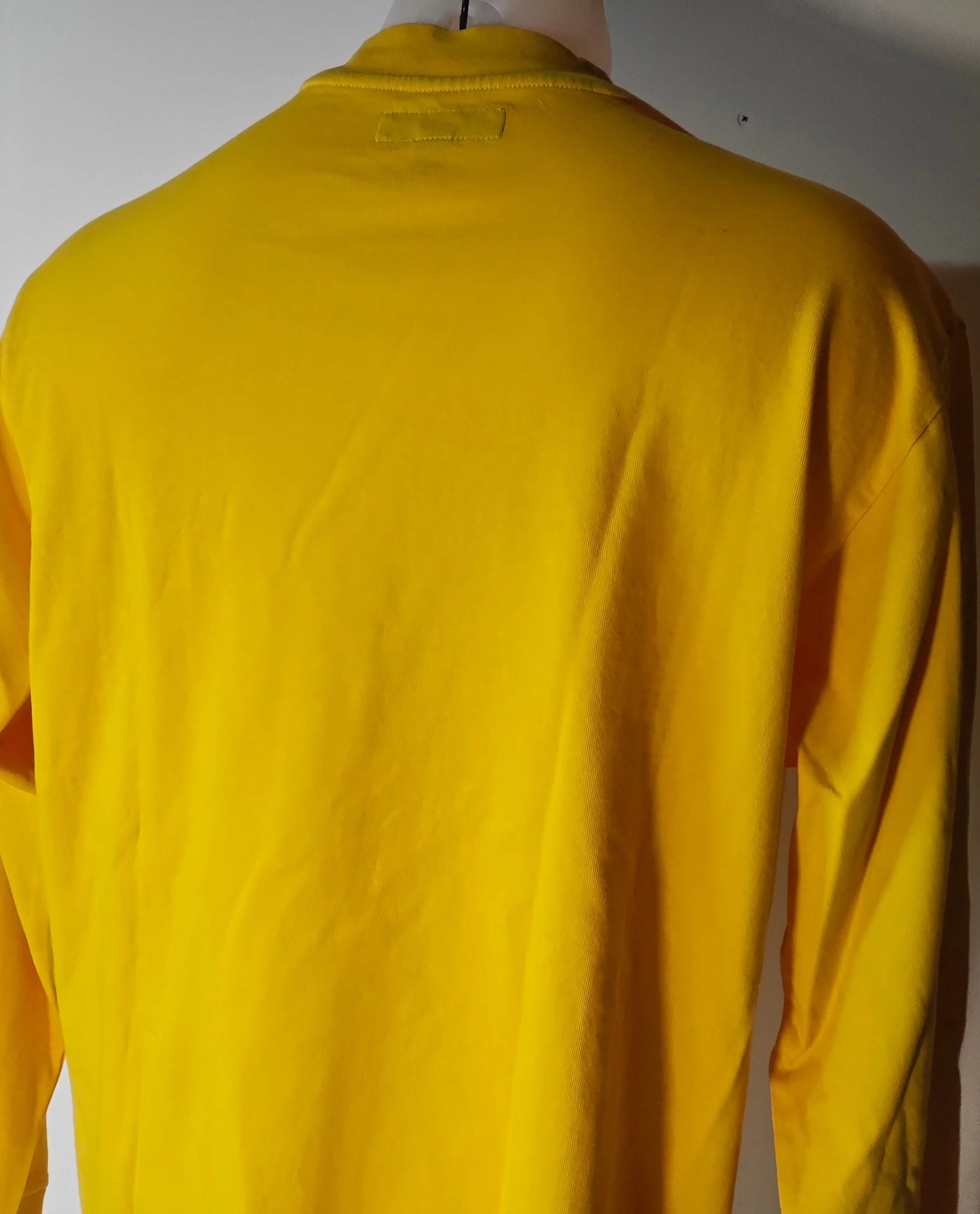 T-shirt jaune à manches longues de Supreme, vu de dos, avec une étiquette au col.