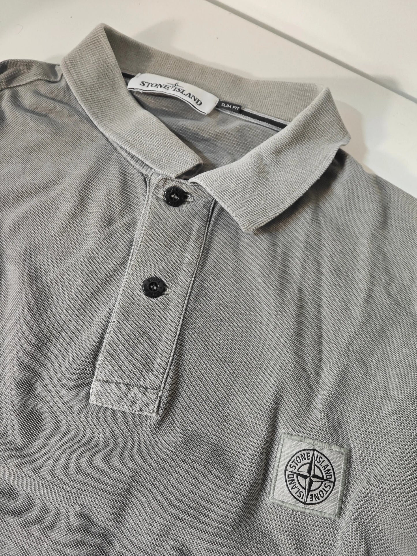 Polo gris en maille piquée de Stone Island, avec col et logo patché sur le devant.