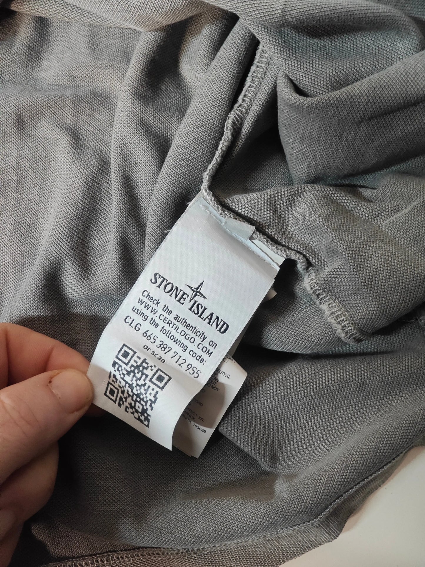Polo gris en maille piquée de Stone Island, avec étiquette d'authentification et code QR.