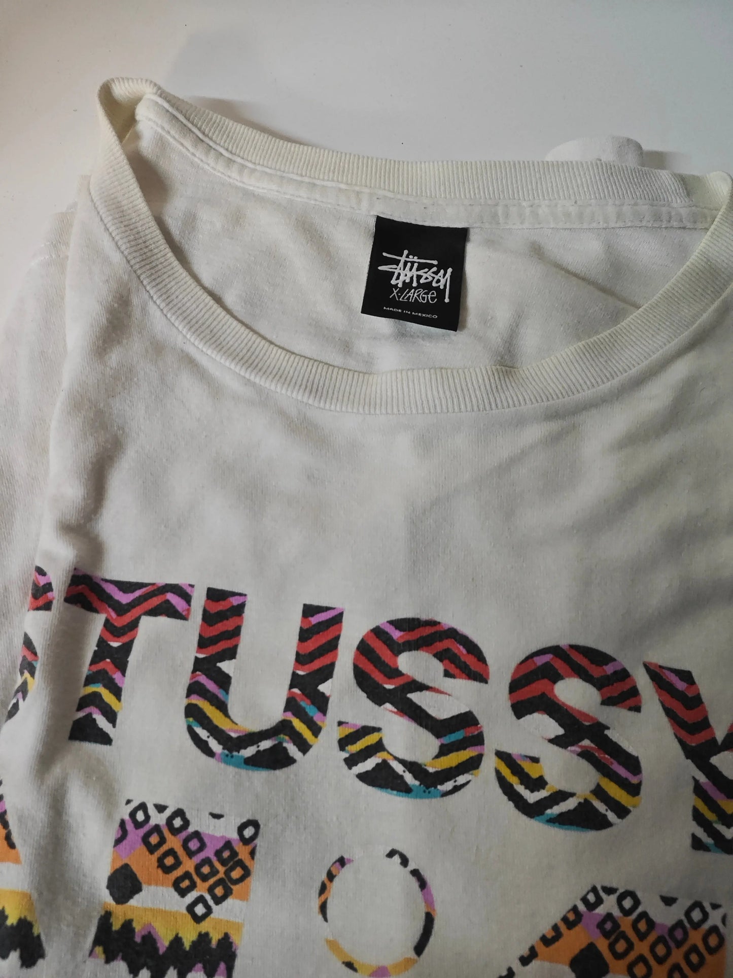 T-shirt crème taille XL de Stüssy, avec logo multicolore et motifs graphiques abstraits.