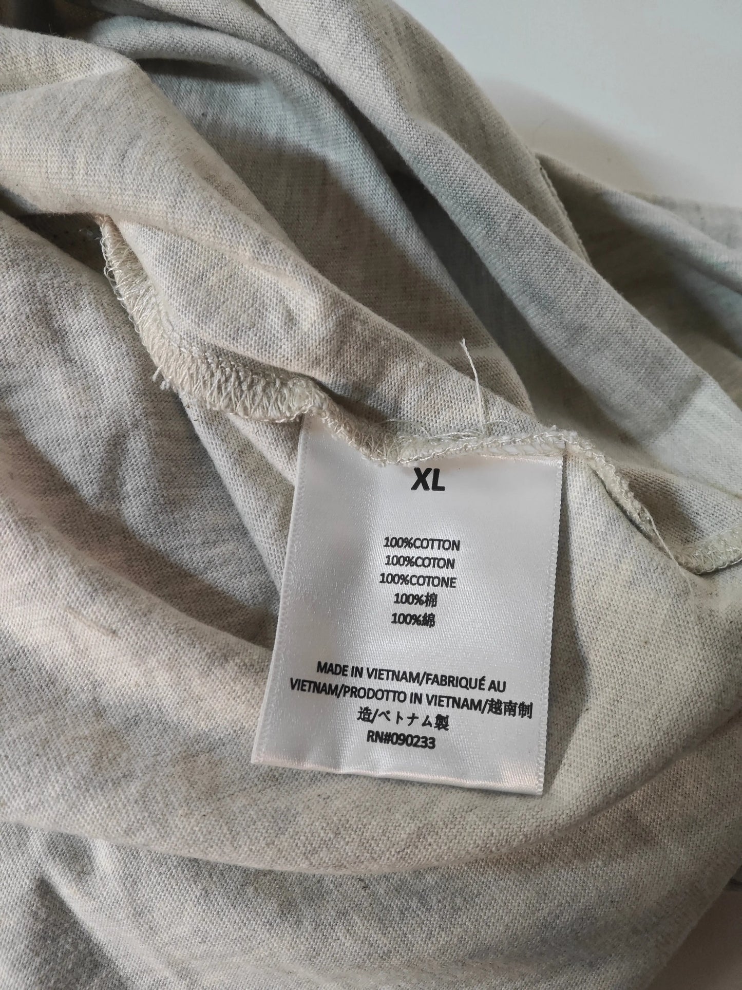 T-shirt beige chiné en coton, Essentials Fear of God, avec étiquette de taille XL apparente.
