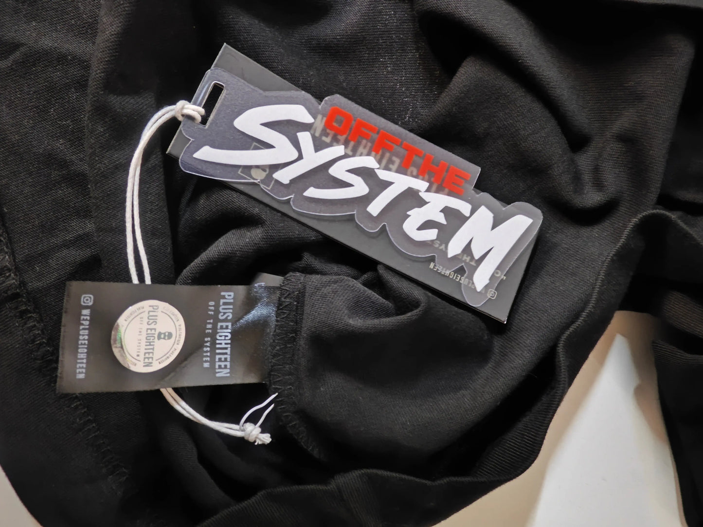 T-shirt noir taille L de Off The System, avec étiquettes et texture plissée visible.
