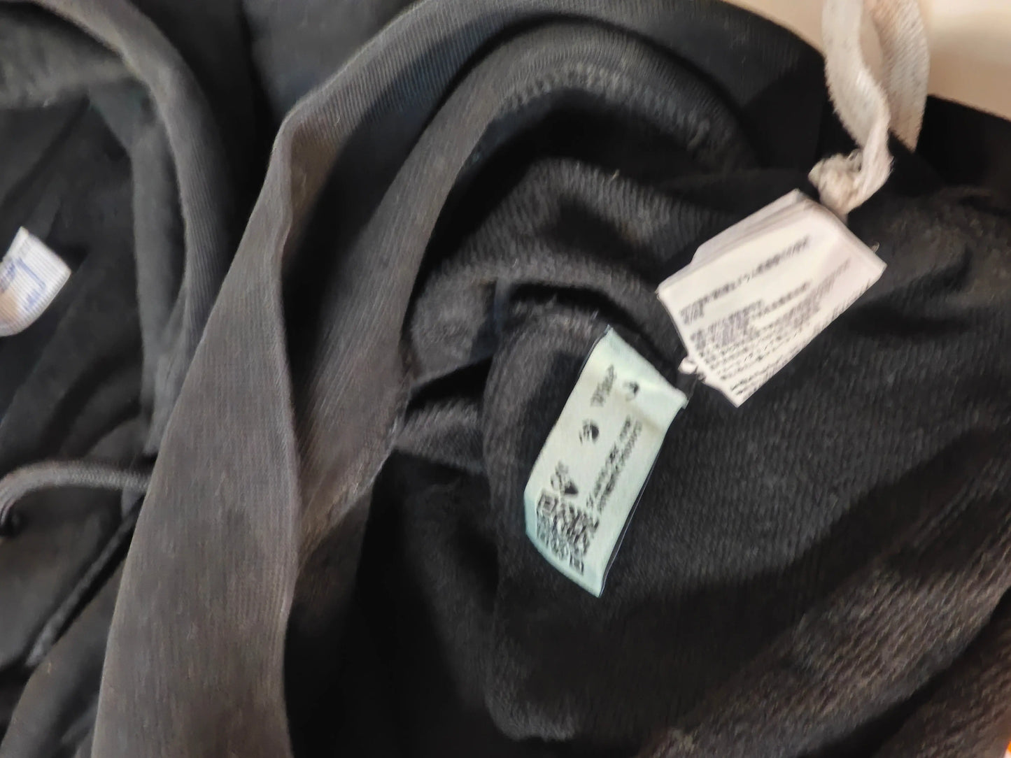 Hoddie noir taille S de Off-White, avec des étiquettes d'entretien visibles et des cordons de serrage.
