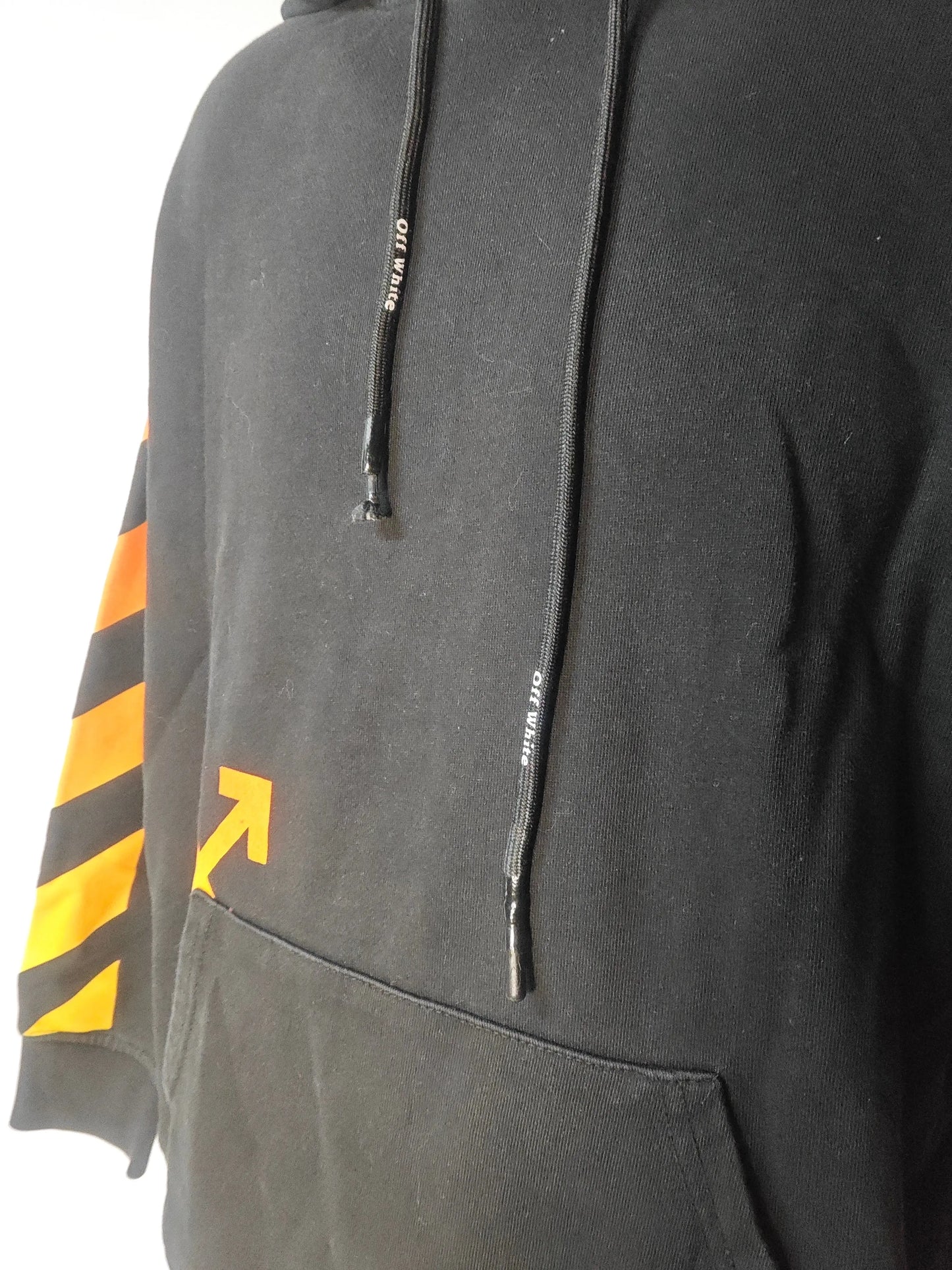 Sweat à capuche noir de Off-White, avec flèche et rayures orange sur la manche et cordons de serrage marqués.
