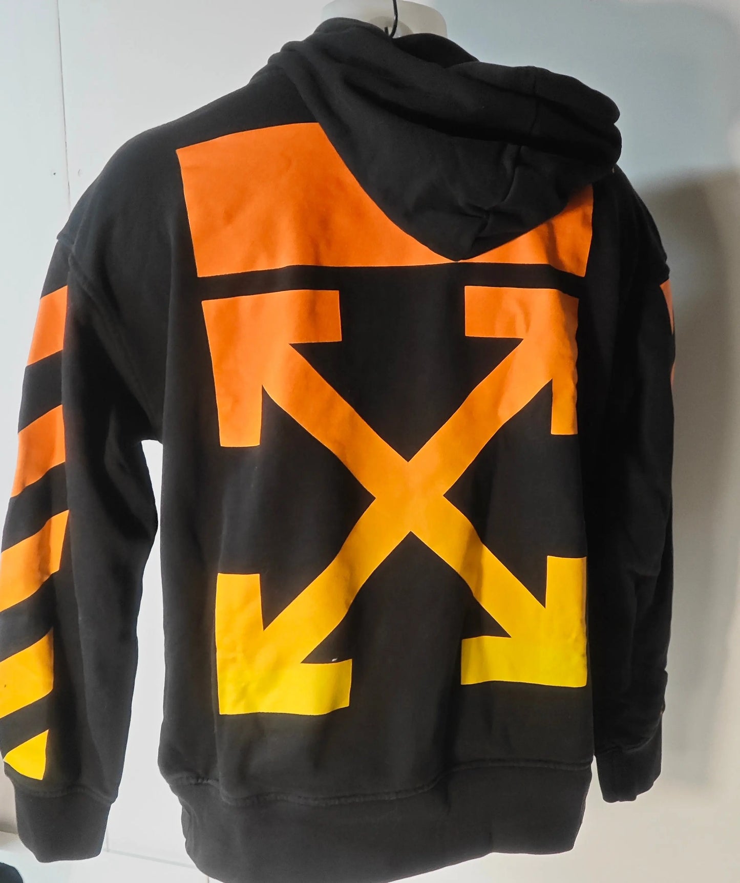 Sweat à capuche noir de Off-White, avec motif flèche orange et jaune au dos et rayures diagonales sur les manches.