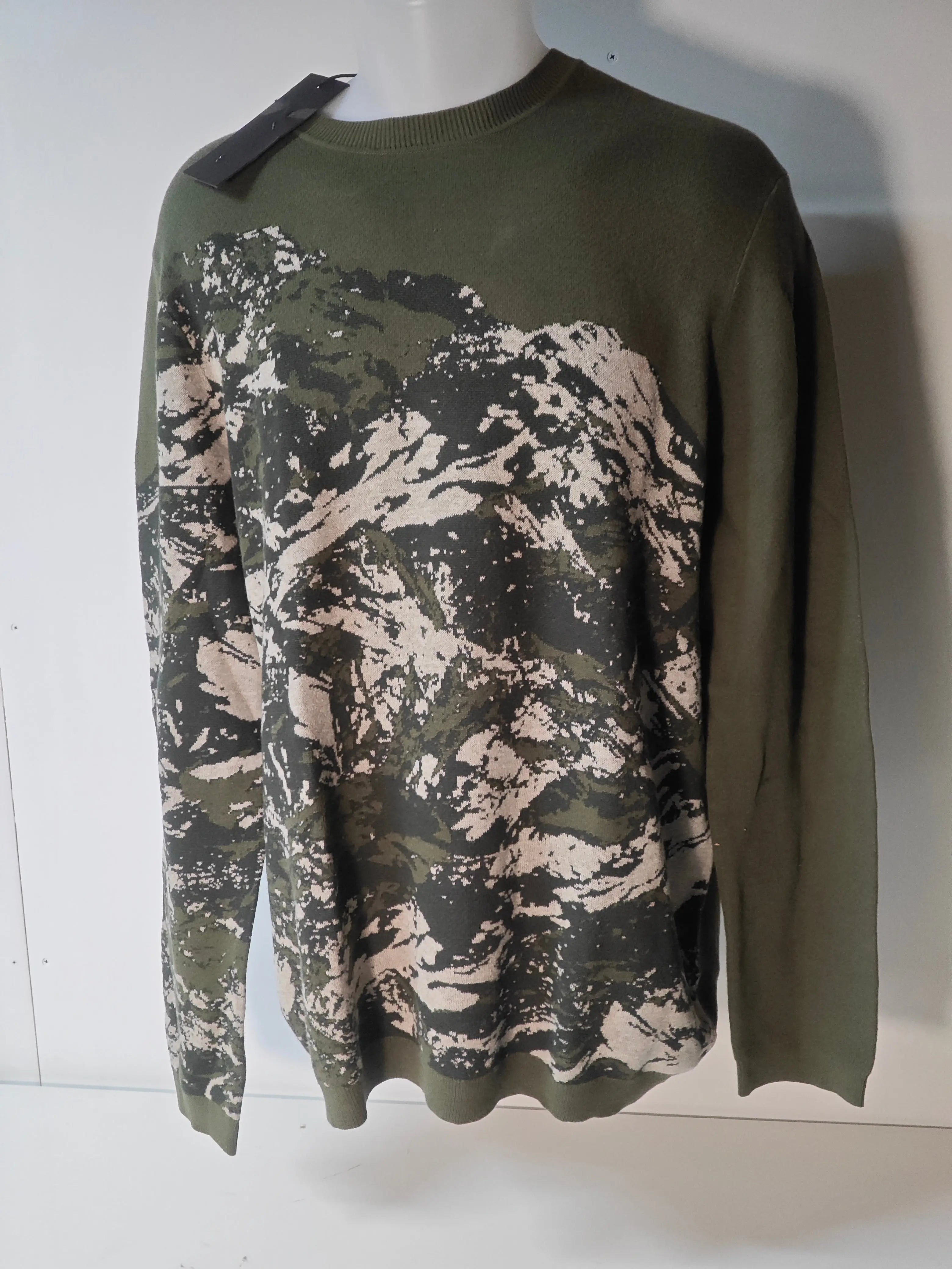 Pull IKKS camouflage en maille, par ikks, avec un motif abstrait sur le devant et une étiquette noire.
