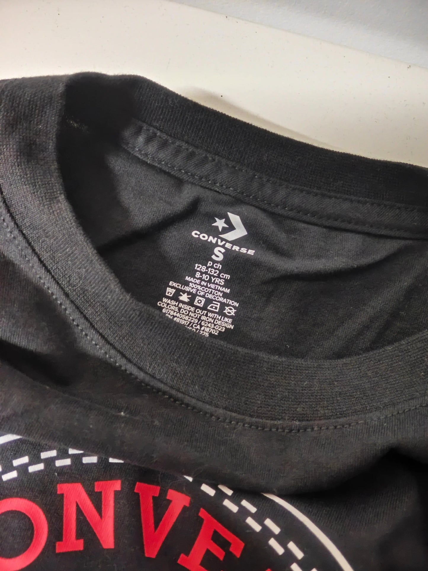 T-shirt noir pour enfant, de Converse, avec l'inscription "CONVE" en rouge et blanc.
