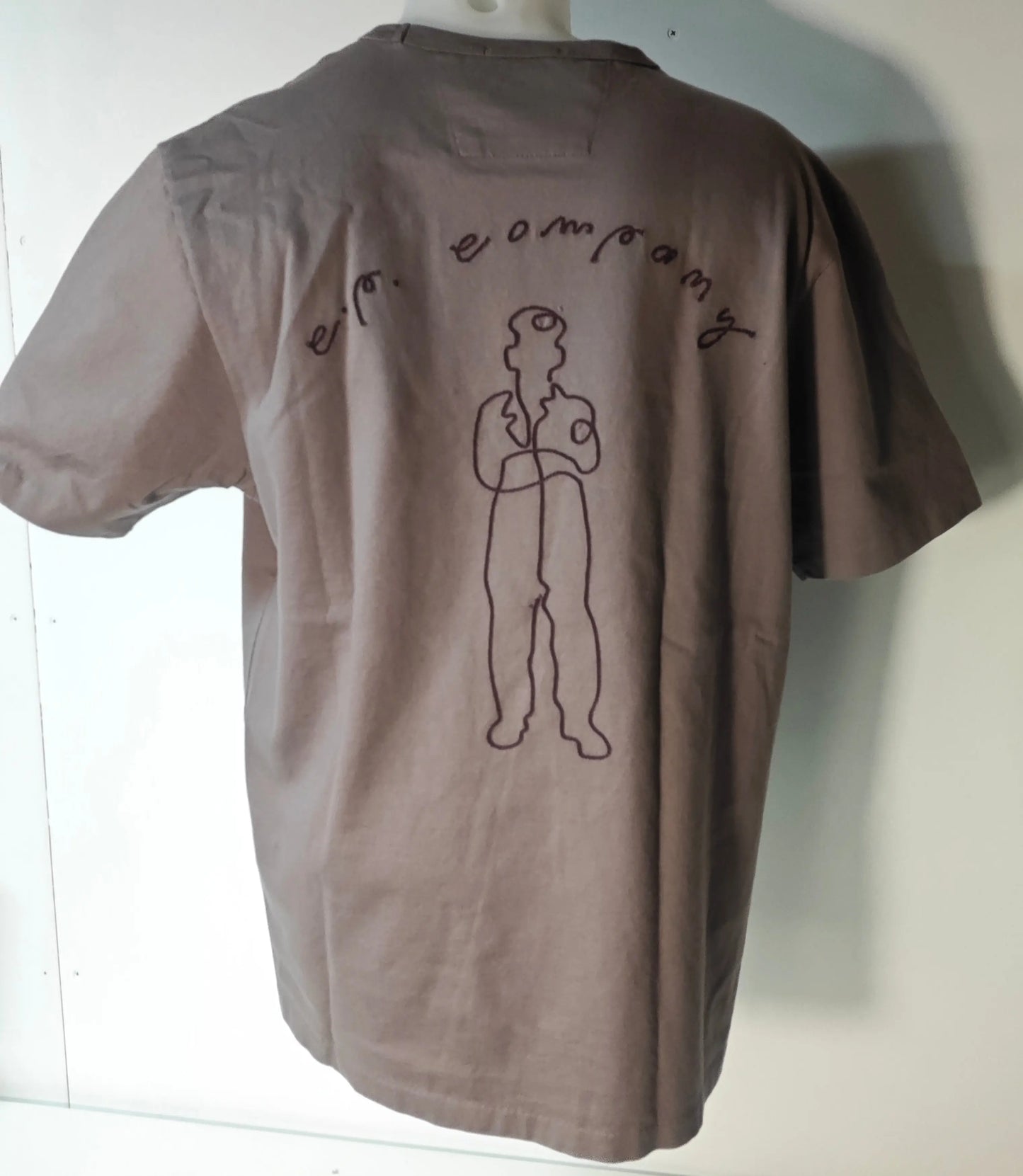 T-shirt marron by C.P. Company avec une illustration d'une personne et lettrage sur le dos.
