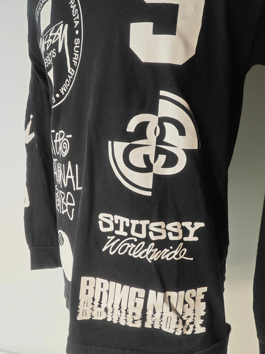 T-shirt noir à manches longues de Stüssy, orné de motifs graphiques blancs variés.