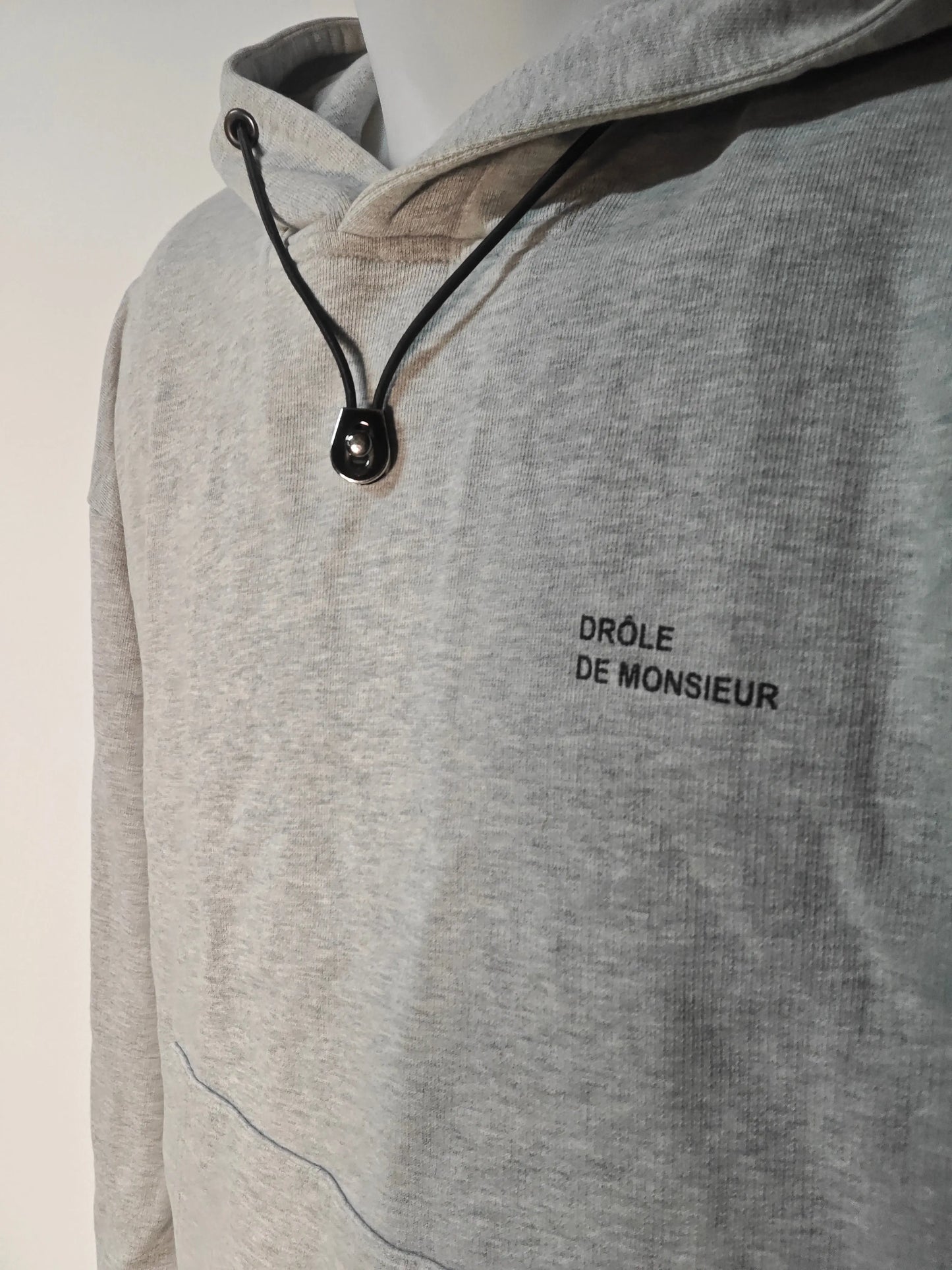 Sweat à capuche gris chiné de Drôle de Monsieur avec cordon noir et logo imprimé.
