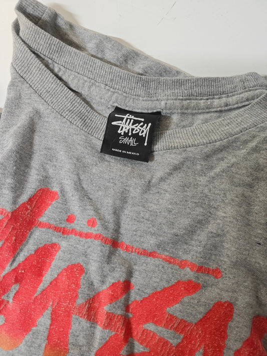 T-shirt gris taille S de Stüssy, avec un imprimé rouge et une étiquette noire sur le col.