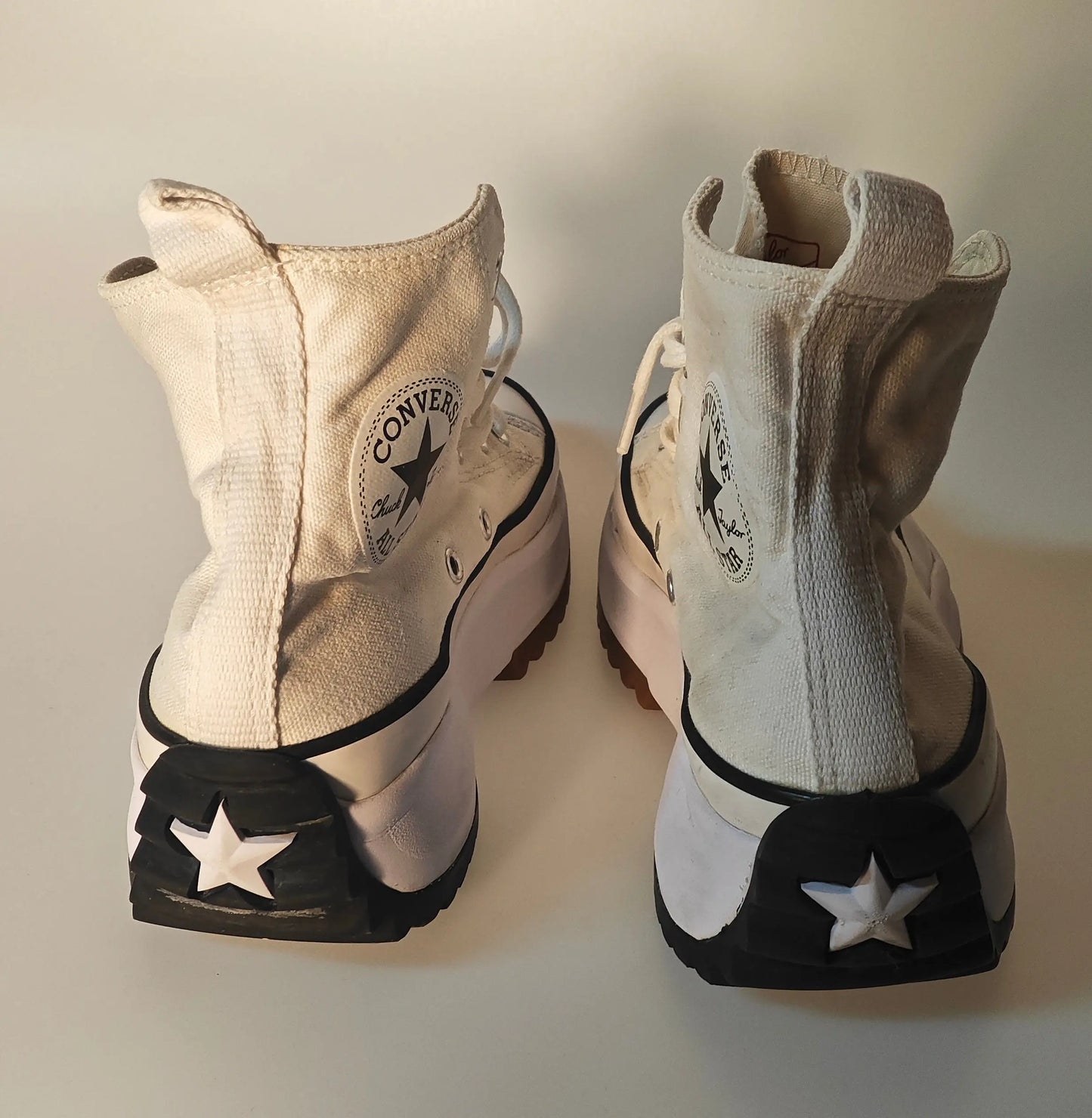 Baskets montantes crème et beiges de Converse, vues de dos avec étoiles décoratives sur les semelles.

