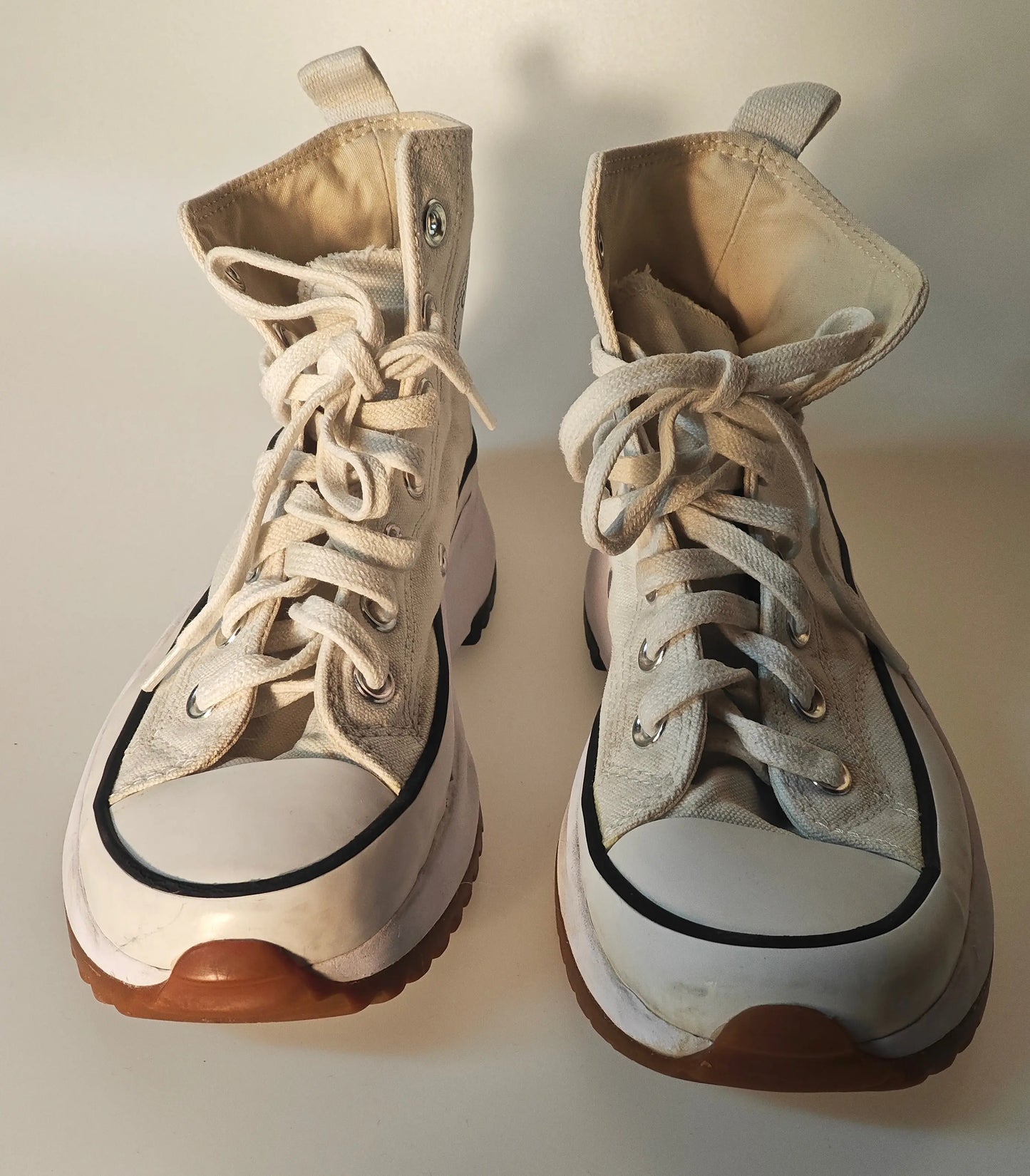 Chaussures montantes crème et beige de seconde main par Converse, avec lacets et semelles épaisses crantées.
