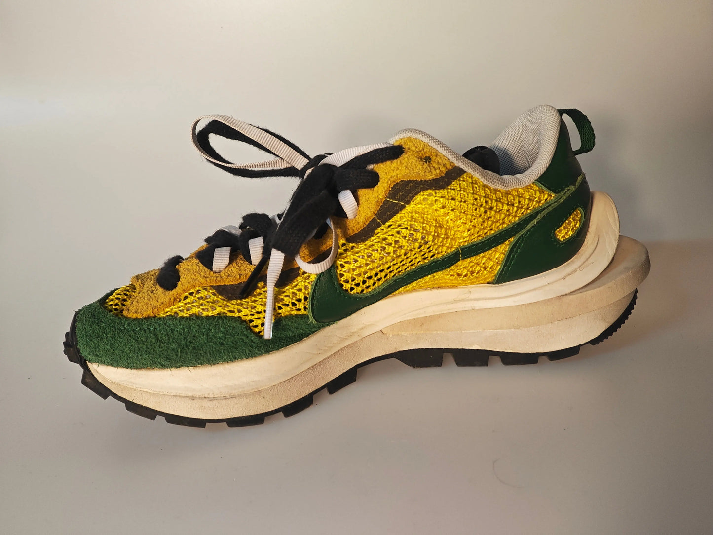 Chaussure de course jaune et verte de Nike, avec semelle épaisse superposée et lacets noirs et blancs.
