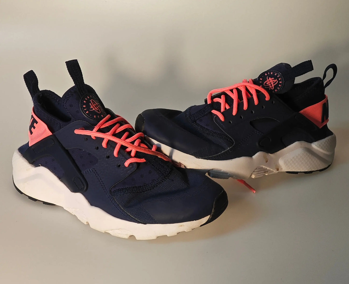 Paire de baskets bleu marine et rose par Nike, avec lacets rose vif et semelle blanche.