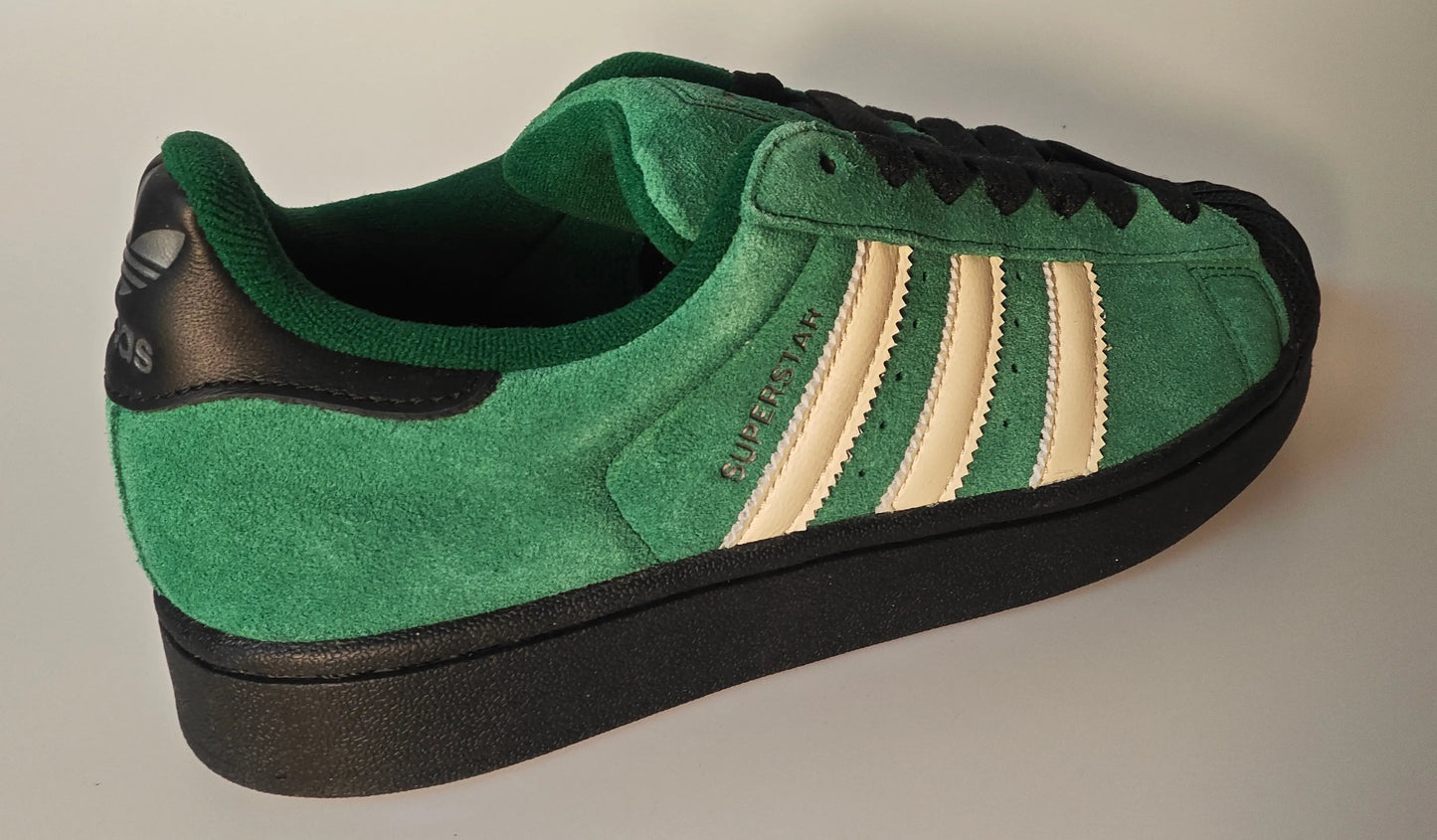 Baskets Adidas Superstar II en daim vert et noir de Adidas, avec des rayures blanches et une semelle noire.
