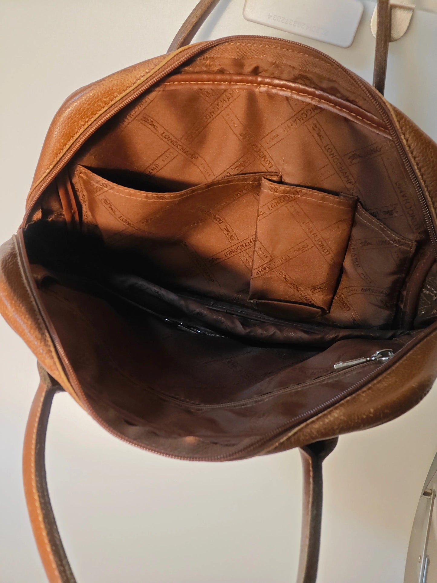Sac à main en cuir marron de Longchamp, avec doublure monogrammée et poches intérieures.

