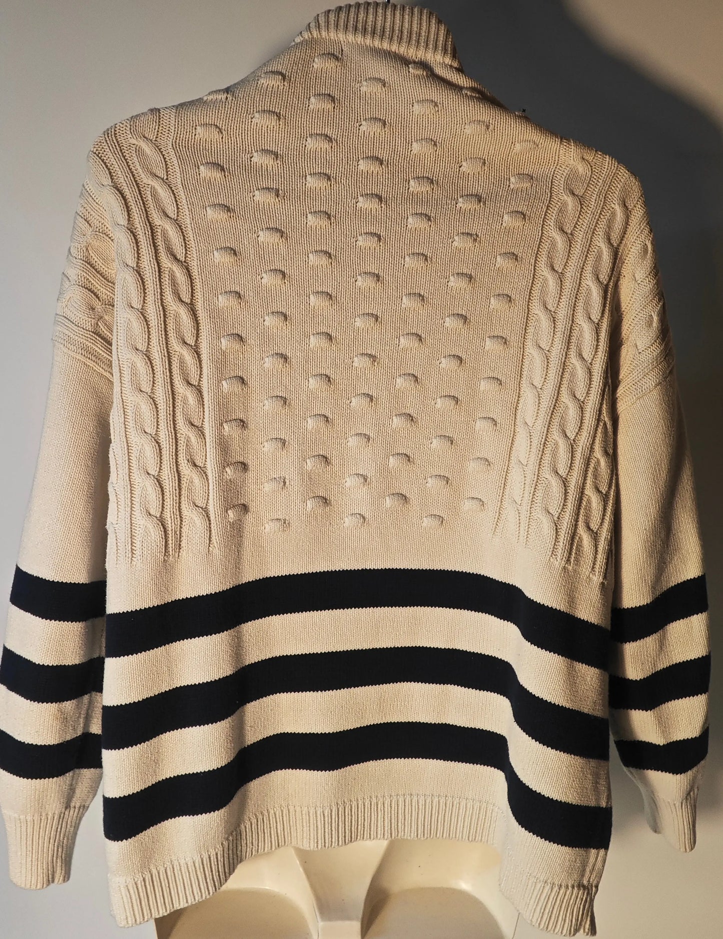 Pull Mango rayé blanc et marine, de Mango, avec des détails en maille torsadée et en points de relief.
