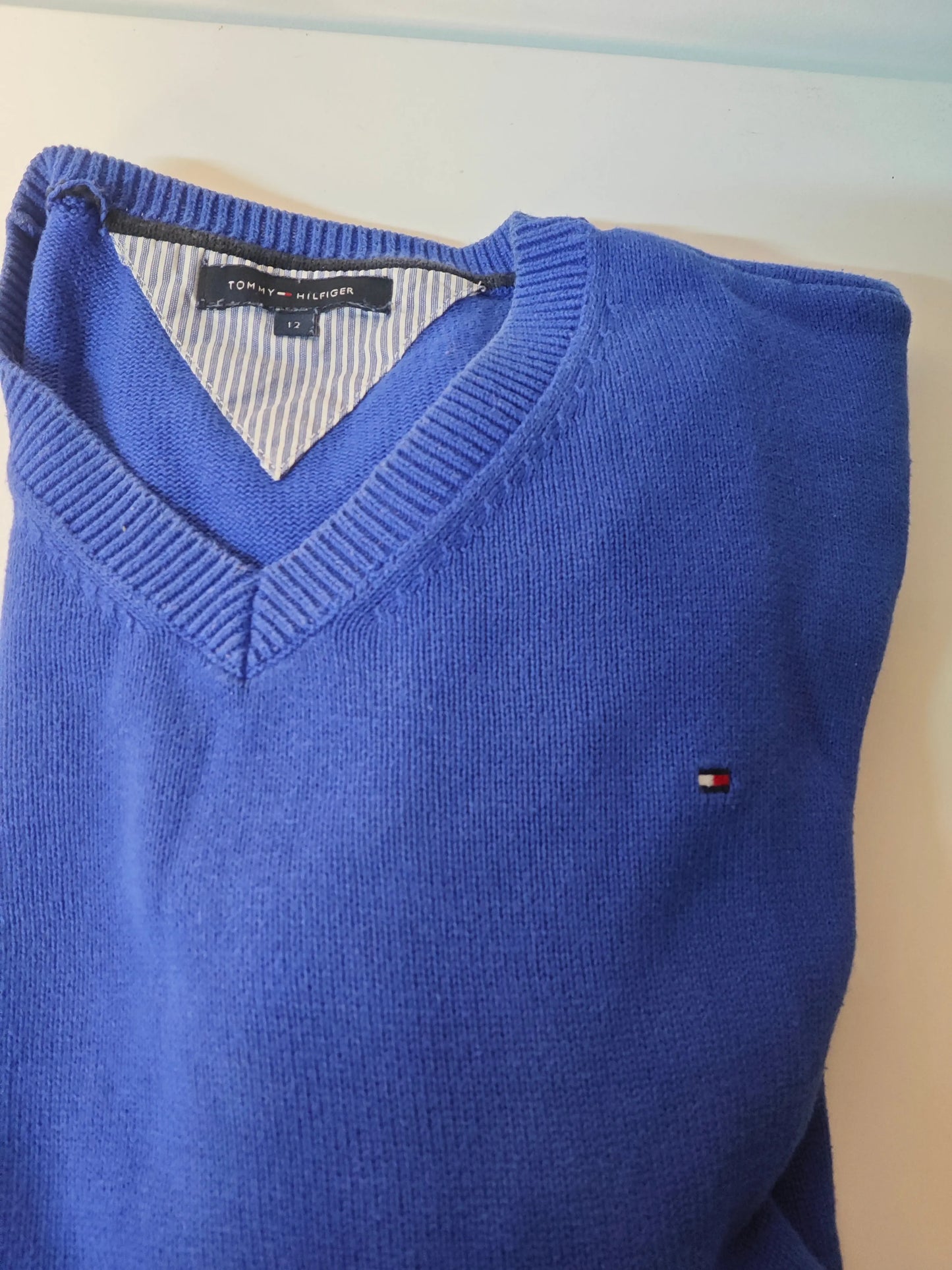Pull bleu en maille, de Tommy Hilfiger, avec un col en V et un logo subtil sur le côté.