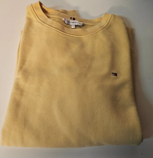 Sweat-shirt jaune de Tommy Hilfiger, plié, avec logo drapeau distinctif brodé sur le devant.