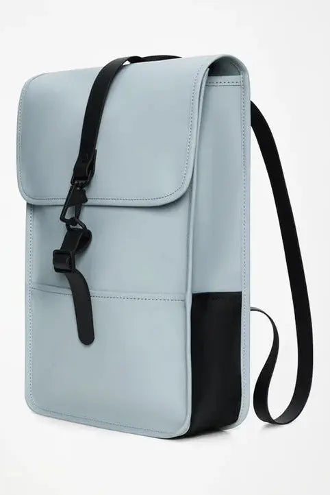 Sac à dos bleu clair de Rains avec une poche avant et une sangle noire.