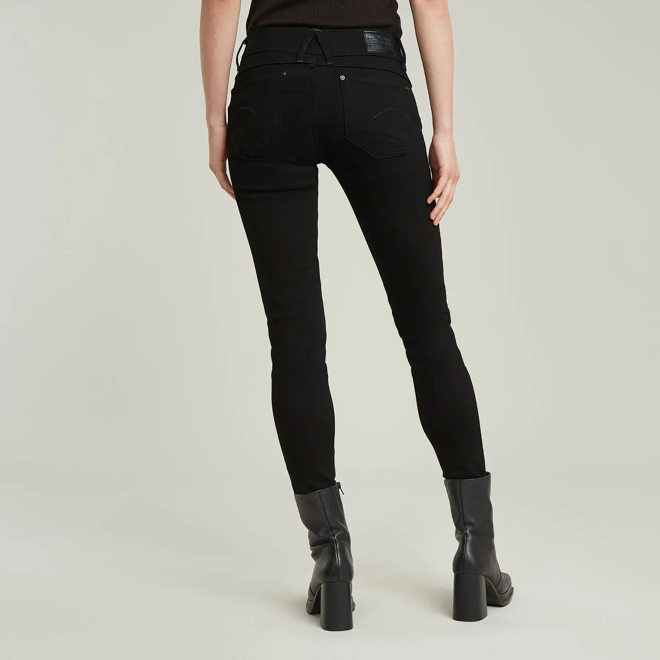Jean skinny noir de G-Star RAW, porté avec des bottes en cuir à talons hauts.
