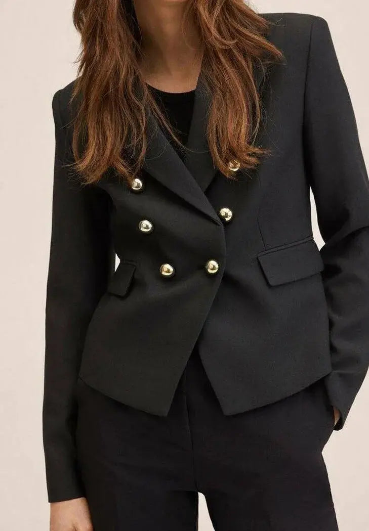 Blazer noir à double boutonnage de Mango, avec boutons dorés et coupe courte.
