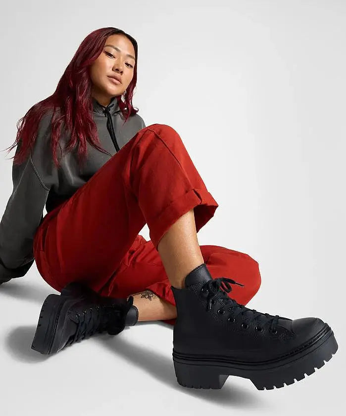 Baskets montantes noires à talon compensé Converse, portées avec un pantalon rouge et un sweat à capuche gris.