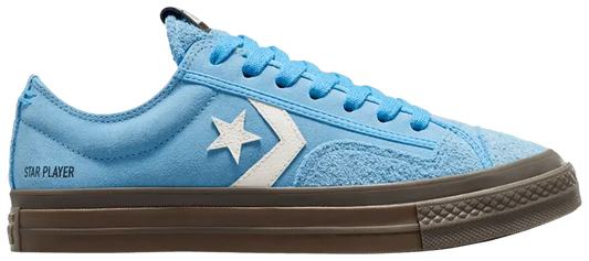 Baskets basses bleues en daim de Converse, avec logo étoile blanc sur le côté et semelle marron.
