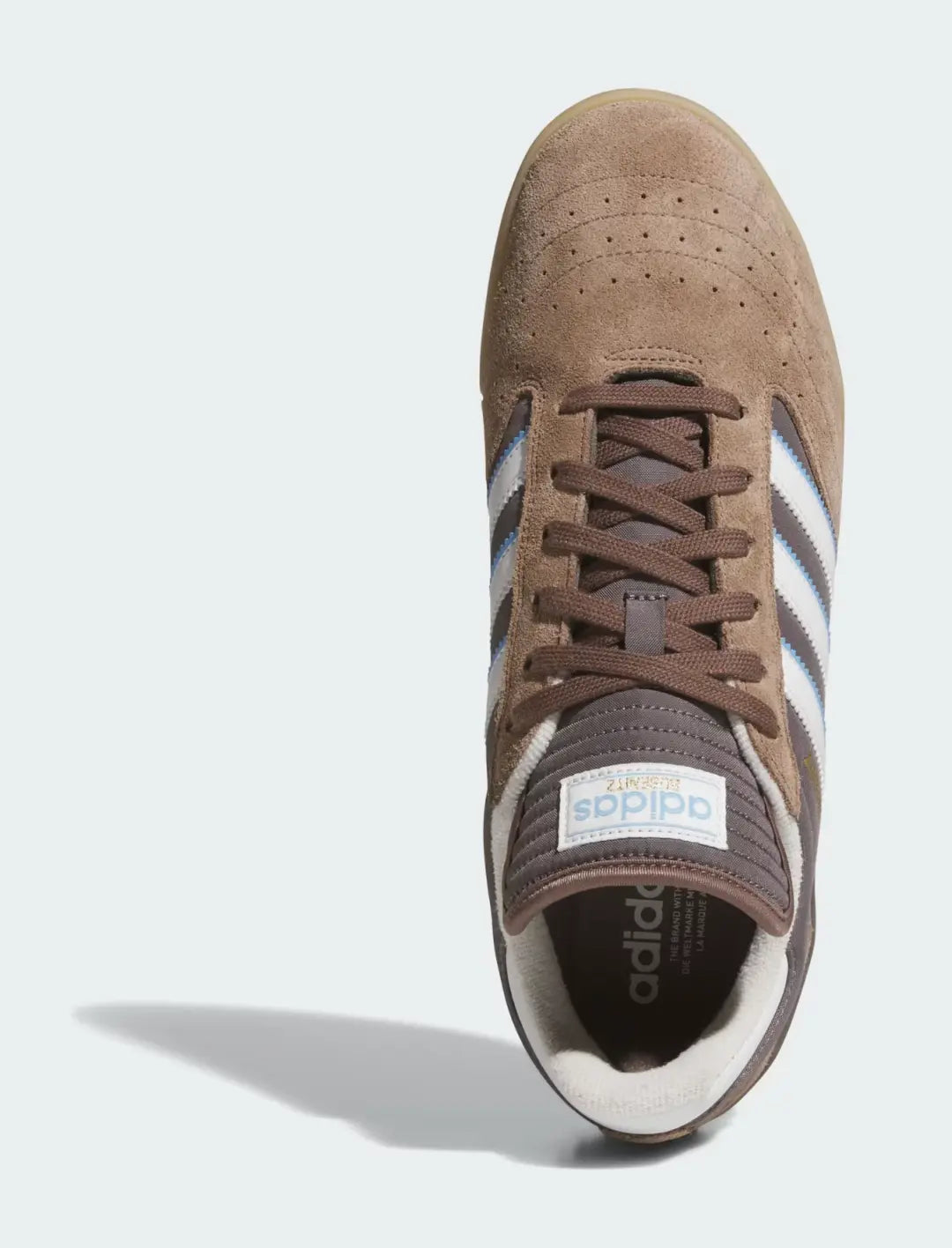 Chaussure de skate marron en daim par Adidas, avec des rayures blanches et bleues sur les côtés.