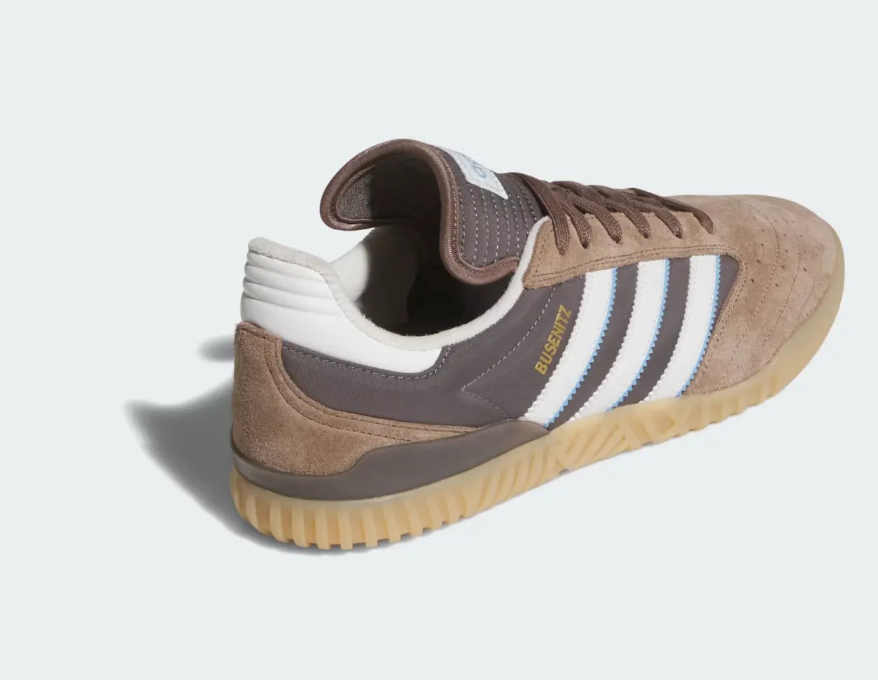 Chaussure de skate marron en daim par Adidas, avec les trois bandes blanches et bleu ciel sur le côté.