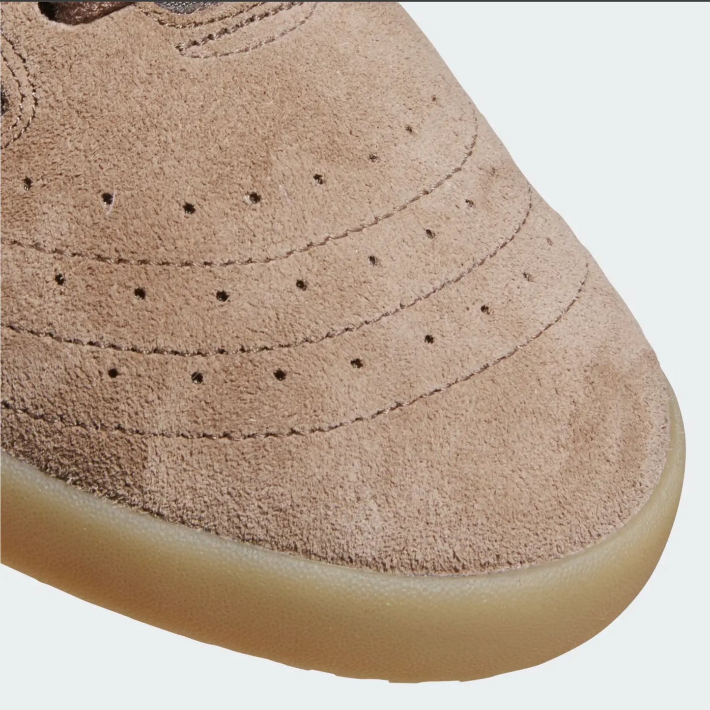 Chaussure de skate en daim marron d'Adidas, avec semelle couleur gomme, perforations et coutures décoratives.