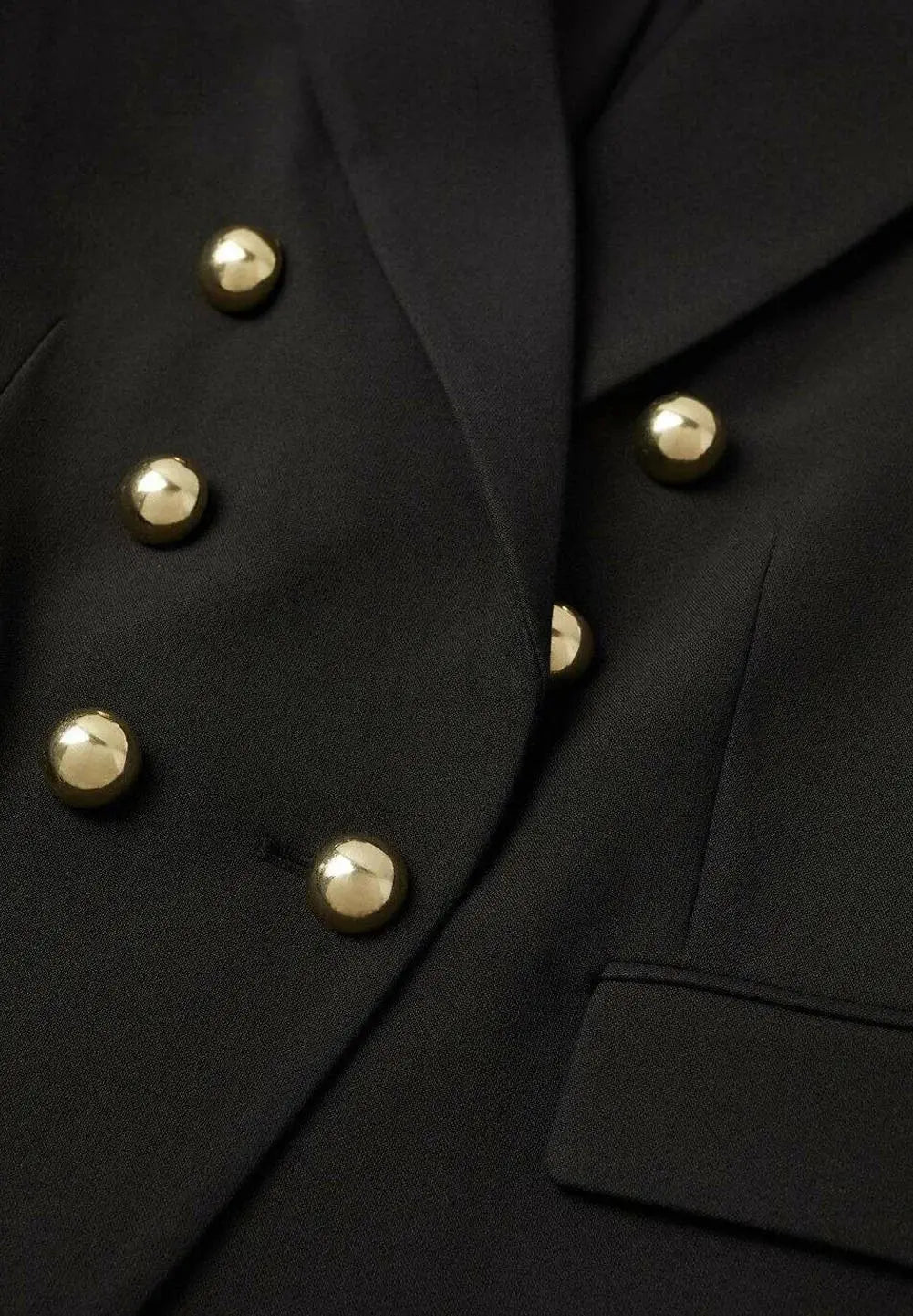 Blazer noir croisé de Mango avec boutons dorés et poche passepoilée.
