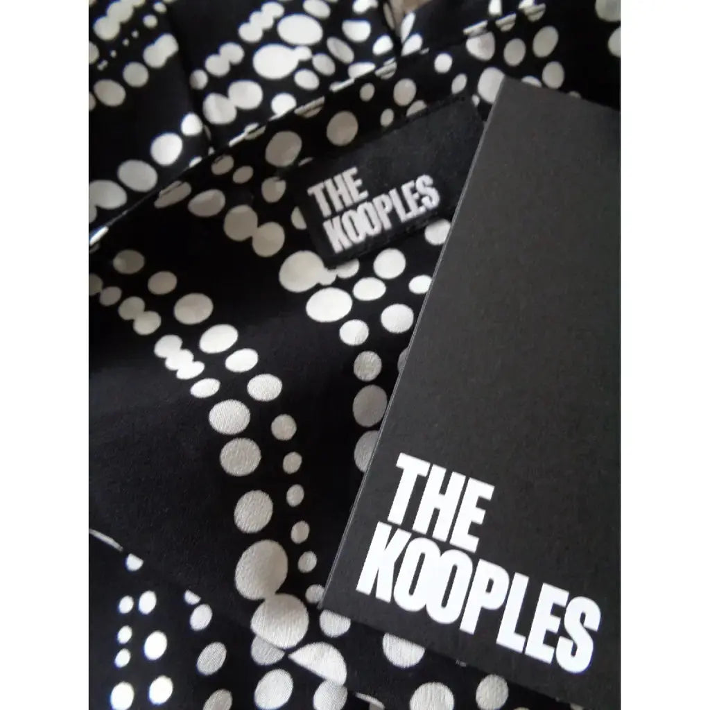 Robe combinée noire à pois par The Kooples, avec une étiquette de marque en gros plan.
