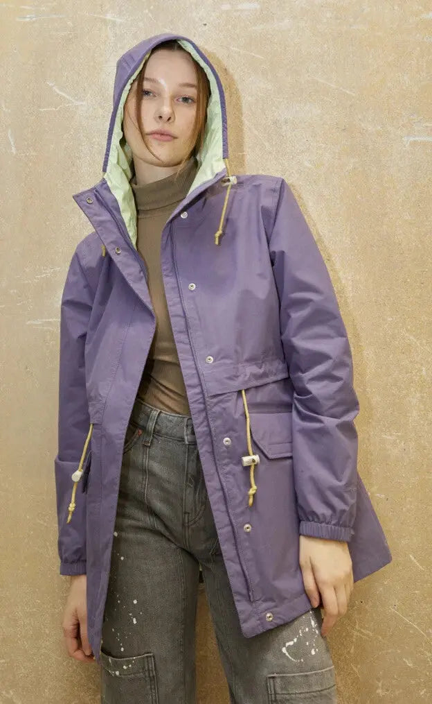 Veste parka DryVent violet lavande pour femme de The North Face, avec capuche doublée menthe, portée avec un col roulé marron et un jean gris.