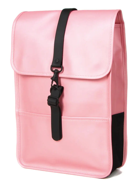 Mini sac à dos rose de Rains avec une fermeture à sangle noire, et un empiècement noir sur le côté.