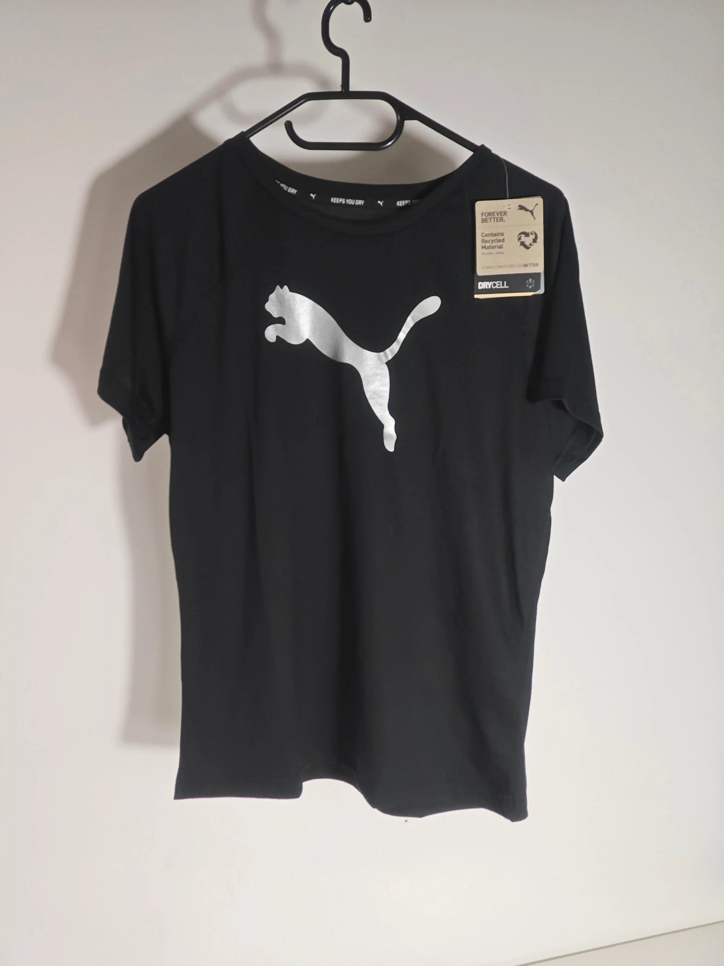T-shirt noir de Nike, orné d'un grand logo argenté sur le devant, suspendu à un cintre.