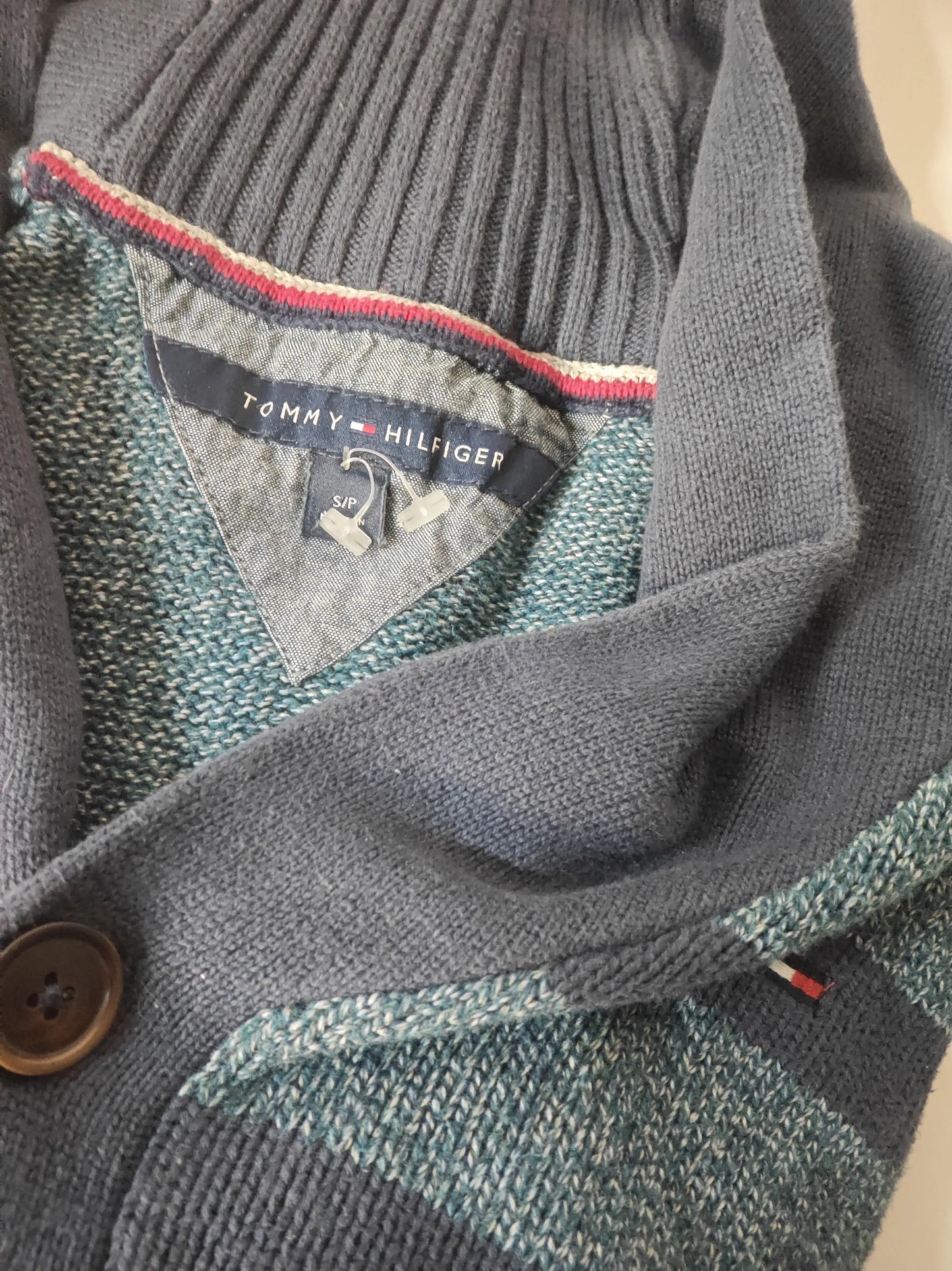 Cardigan bleu marine de Tommy Hilfiger, en tricot avec rayures décoratives et un bouton, étiquette de taille visible.
