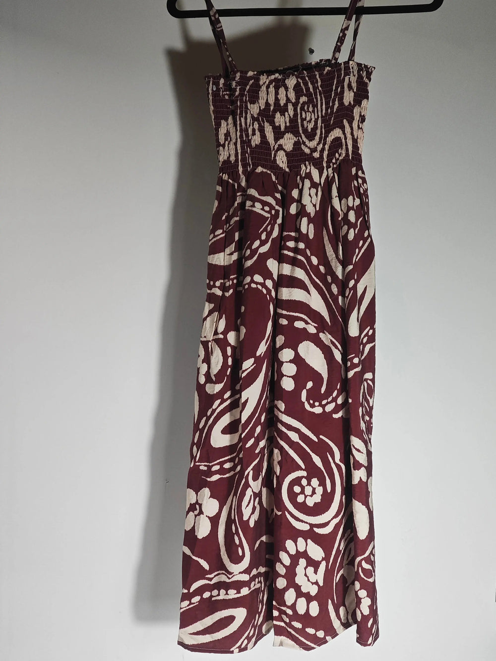 Robe taille unique bordeaux et beige d'Upstyle Destock, avec un imprimé cachemire all-over, suspendue à un cintre.